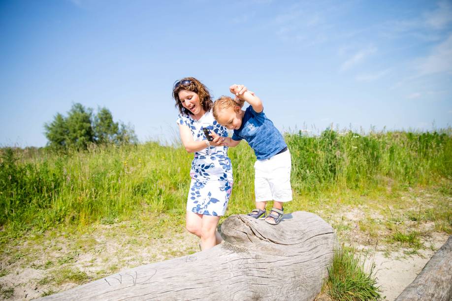 Kinderfoto van peuter die met hulp van moeder over boomstam loopt. Gemaakt door fotograaf Ilse Zomerman